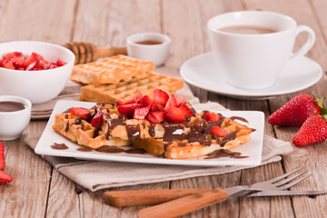 Waffles with strawberries and chocolate cream.
