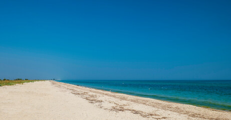 Beautiful seascape. Big beach, lots of sand and water. Summer vacation by the sea. Clear sky blue