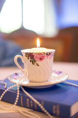 Tea cup and plate with hand painted roses draped in pearls on a blue bible