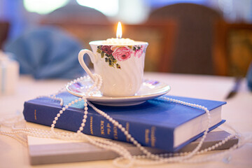 Tea cup and plate with hand painted roses draped in pearls on a blue bible