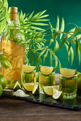Bottle and glasses of tequila with lime on a wooden table. Traditional Mexican alcoholic beverage....