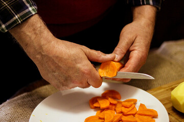 A man cuts carrot into slices to make soup