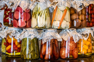 Оrganic сanned pickled fermented vegetables in glass jars with paper lids. Autumn and summer harvest at the farmers' market. Homemade organic food. 