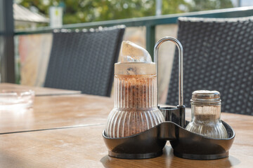 Spices Chilli Pepper bottle glass jar on wooden table at an outdoor restaurant
