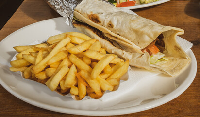 Kebab and French fries recipe on a white dish table in an European country.
