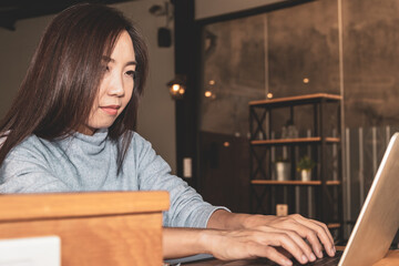 Smart beautiful clever Asian female thinking of serious information of summary positive study and business script essay in front of computer laptop at modern office table with the comfort atmosphere