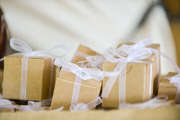 Miniature  brown cardboard gift boxes wrapped with white bows and laces inside of canvass basket