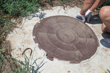 The man opens the manhole cover of the water well. Checking and fixing water metering.