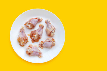 Fresh raw chicken wings (wingstick) in white plate on yellow background.