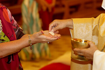 Communion rite during mass in a Catholic church. Priest give host in the hands of a faithful
