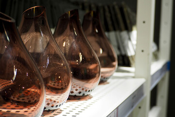 four brown glass vases stand on a shelf in the room