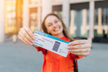 Caucasian girl joyful holding an air ticket for the plane and travel in her hands