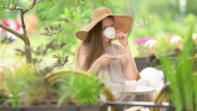 Beautiful young girl in a hat sitting at the street cafe looking away drinking morning coffee or tea. spending relax outdoor