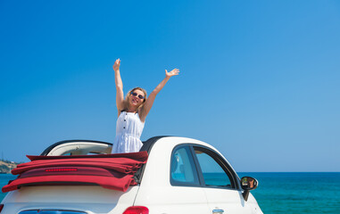 A summer cabriolet trip. A young beautiful girl behind the wheel of a car. Happy girl on vacation.