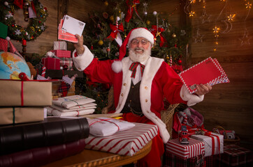 Santa Claus rejoicing with letters and mail in his post office indoors Log Cabin at the North Pole
