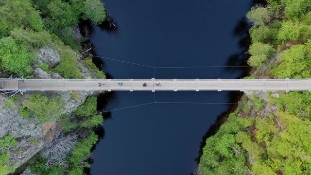 dronedrone shot of 4 persons crossing a suspended bridge in Aiguebelle National Park, Quebec, Canada