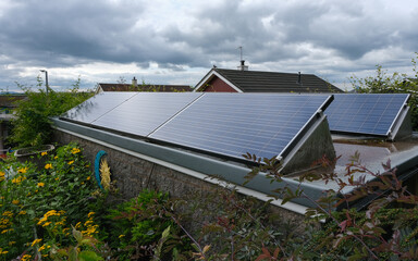 Solar panels on a shed roof in a garden on a cloudy day