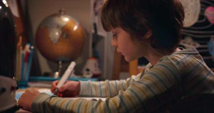 Dreaming about travel. Cute creative little boy child drawing at home table looking up, imagining future profession.