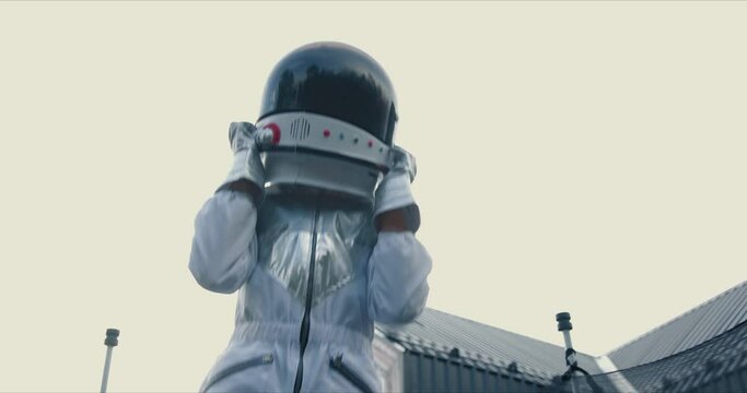 Dreaming about space travel. Little astronaut child jumps on trampoline outside wearing white space suit and helmet.