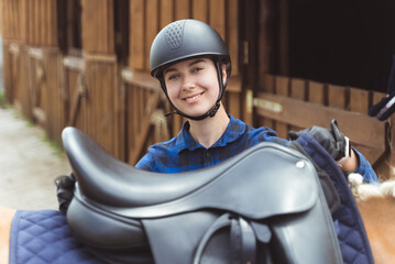 Female jockey standing with her horse outside the horse stable. The jockey is ready for the horse...
