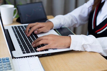 Young woman sitting, using laptop, tablet, notebook and calculator working from home. Closeup shot...