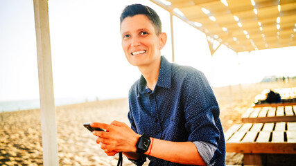 A woman of androgynous appearance and a watch on her hand smiles