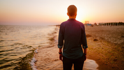 A woman of androgynous appearance stands with her back at sunset