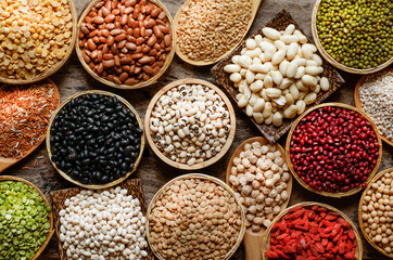 Collection of dry organic colorful cereal and grain seeds in wooden bowl in dark tone, consisted of bean, flax seed, goji berry, rice, peanut, job's tear, mung, and corn, for healthy food concept