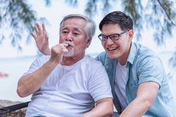 Obraz premium Asian young man take care and warn hug father, he is very happy and smile in outdoor background.