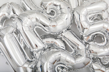From above of full frame background of various silver number balloons scattered on white table