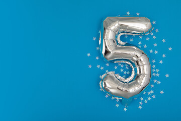 Silver balloon 5 on a blue background with confetti stars. Number five 5. Holiday Party Decoration...