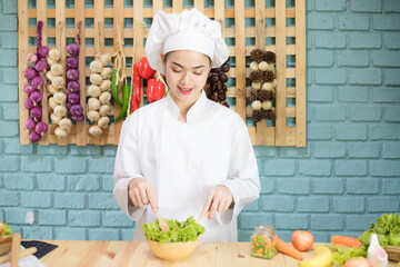 Beautiful young Caucasian woman wearing chef is cooking in the kitchen.