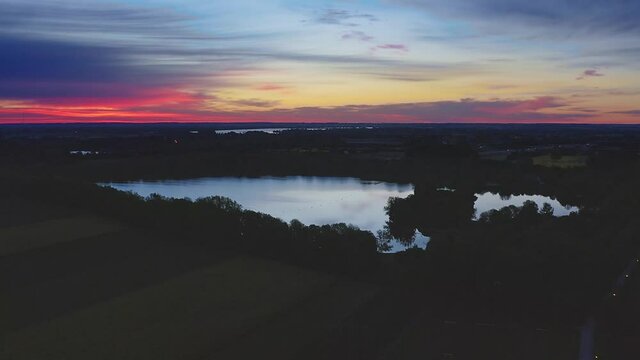 Panning shot around a lake in the twilight of the red glowing sunrise - beautiful nature is awakening.