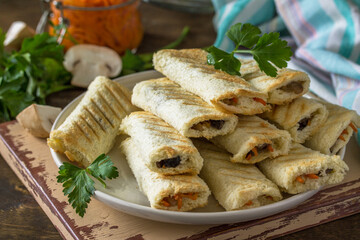 Fast breakfast. Bread toast roll sandwich with mushrooms and carrots spices on a rustic table.