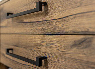 Close-up of modern dark wood furniture with black handles.