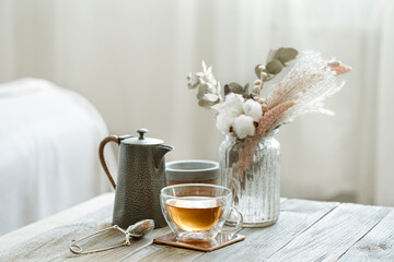 Cozy home composition with a cup of tea, teapot and Scandinavian decor details.
