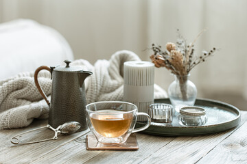 Cozy home composition with a cup of tea, teapot and candles.