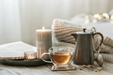 Cozy composition with a cup of tea, a teapot and candles.