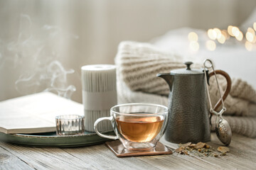 Cozy composition with a cup of tea and a teapot on a blurred background.