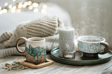 Cozy still life with ceramic cups with tea and a knitted element.