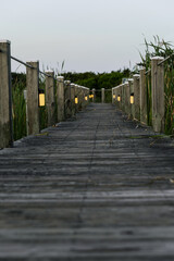 Walkway at the beach made of wood with grass growing on the sides. 