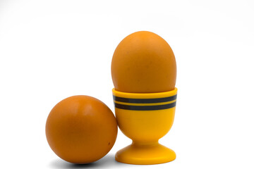 Brown eggs and bright yellow egg cup isolated on white background.