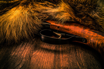 Hunting rifle lying next to the animal's fur produced. View close-up