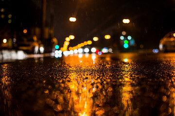 Rainy night in the big city, approaching headlights of cars traveling along the avenue. View from...
