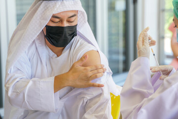 woman Nurse preparing injecting vaccine to shoulder of Arab Muslim man in clinic or hospital for...