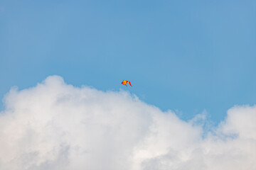 Colorful kite flying in the blue sky with beautiful white clouds