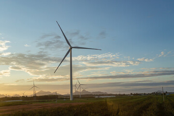 Windmill in front of blue and yellow dawn sky and white clouds