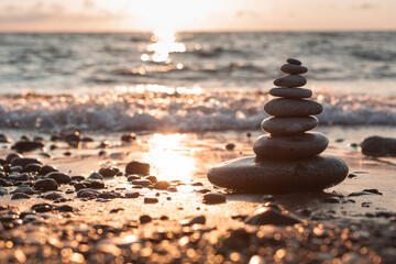 Pyramid of stones on the beach at sunset, beautiful seascape, rest and seaside vacation concept. 