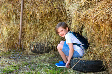 smiling happy boy sitting at haystack on farm