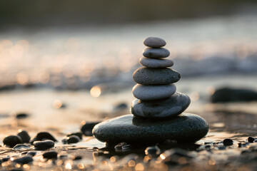 Pyramid of stones on the beach at sunset, beautiful seascape, rest and seaside vacation concept. 